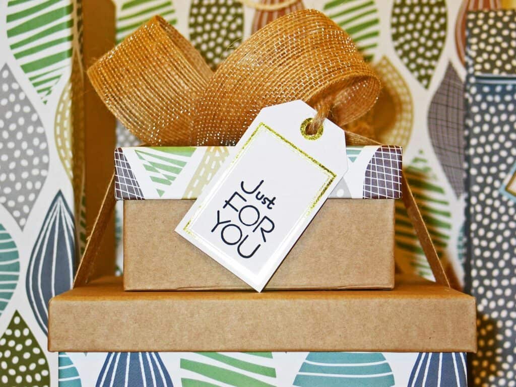 Holiday client gift wrapped in patterned paper with a gold ribbon and a tag reading "Just for You."