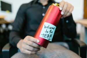 Man holding onboarding kit, packaged in red metallic tube with note that says "welcome to the team."